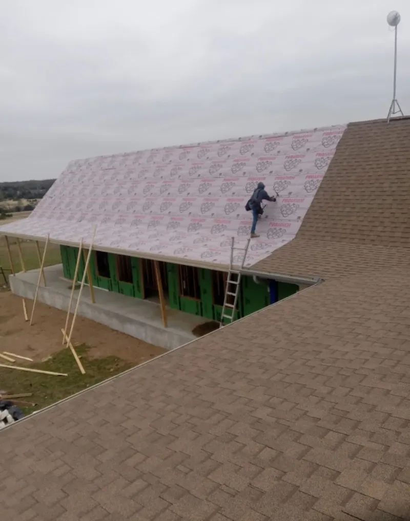 Worker preparing underlayment for a metal roof installation in Cherry Hill
